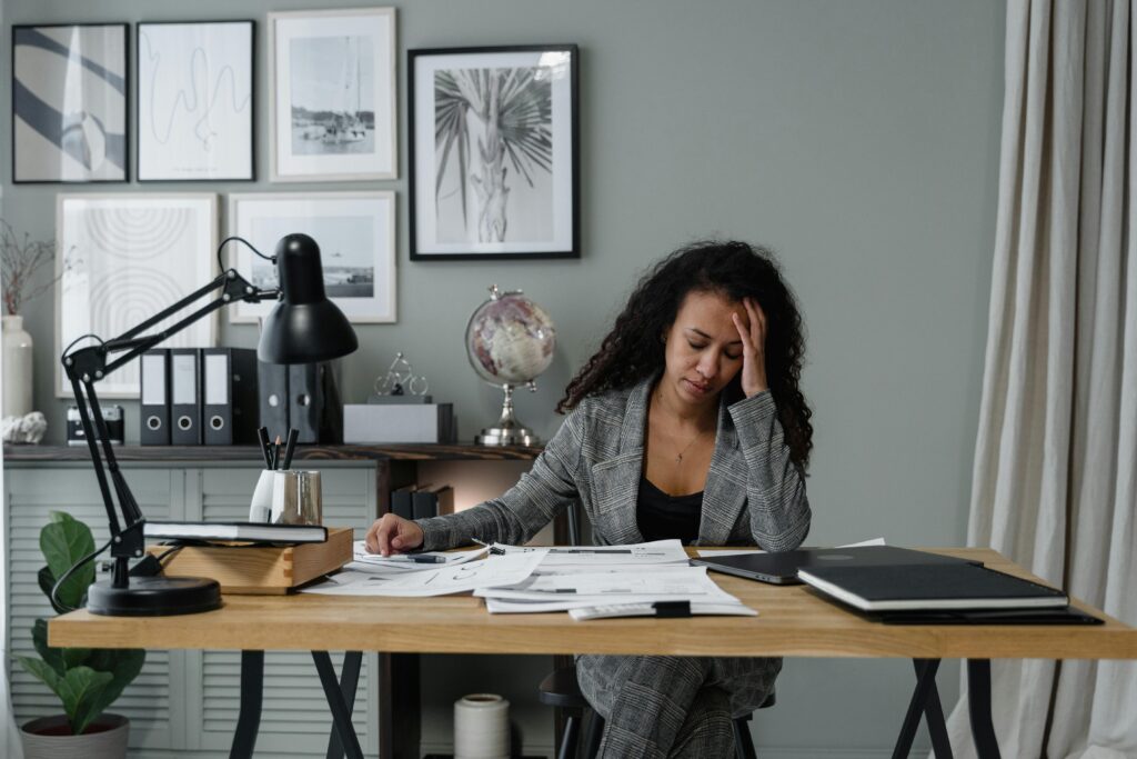Female founder experiencing burnout — exhausted at her desk after working long hours